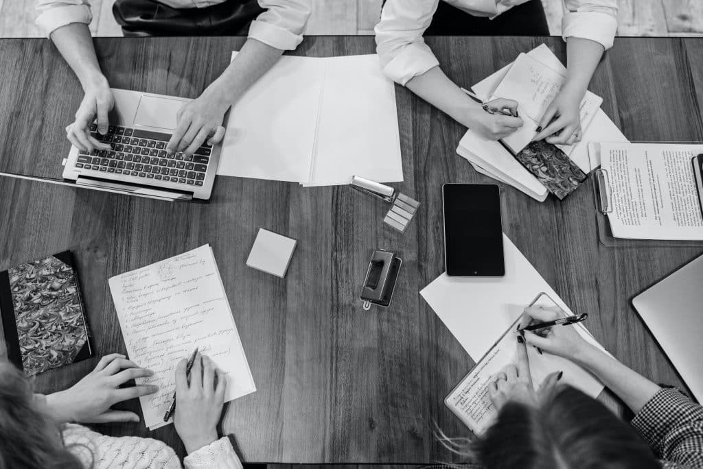 People Writing and a Person Using a Laptop